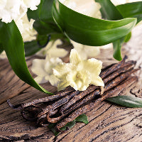 Madagascar Vanilla beans with a vanilla flower on a wooden surface